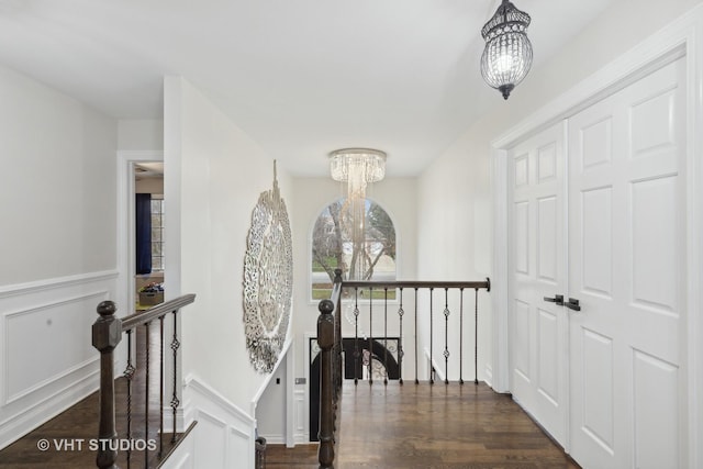 hallway featuring dark wood-type flooring and a notable chandelier