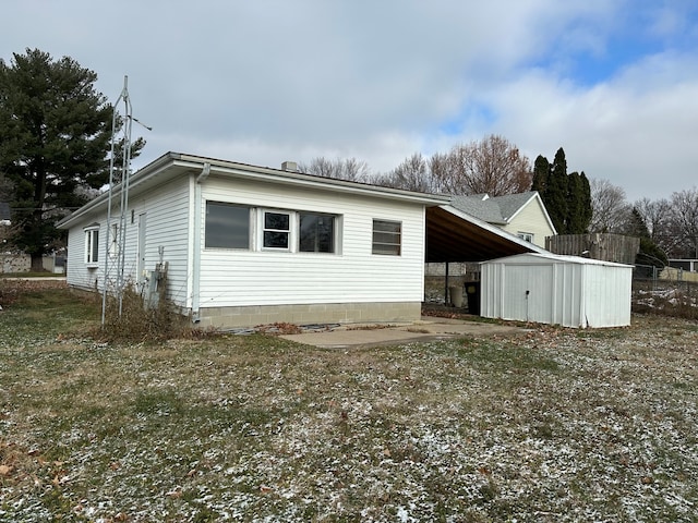 rear view of house with a carport and a storage unit