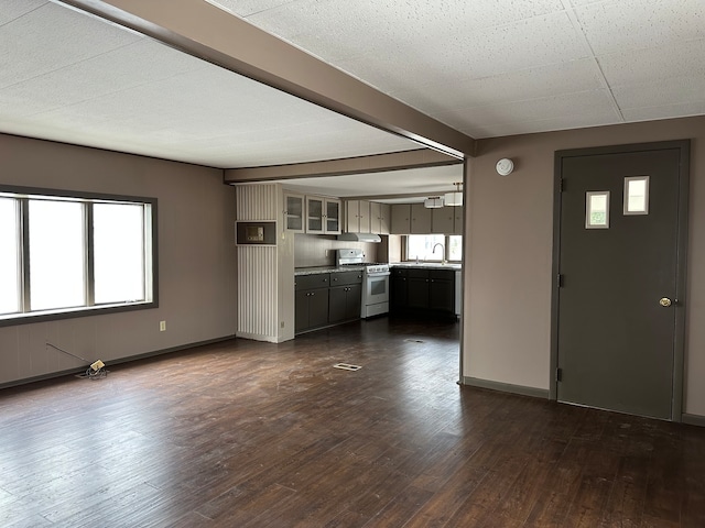 unfurnished living room with beam ceiling, sink, and dark wood-type flooring