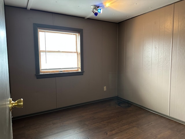 empty room with dark hardwood / wood-style flooring and wooden walls