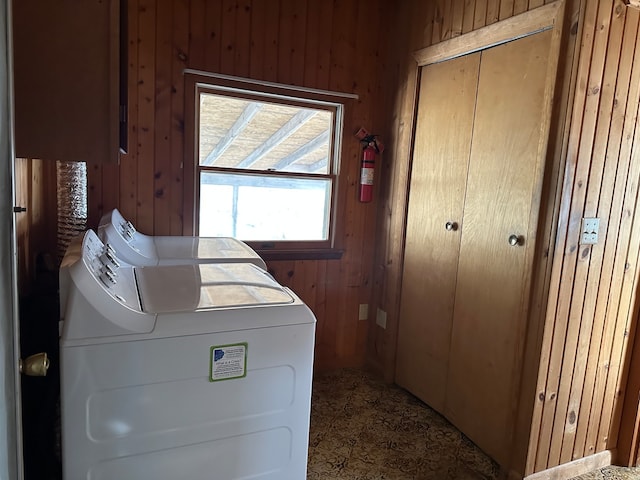 washroom featuring washing machine and clothes dryer and wood walls