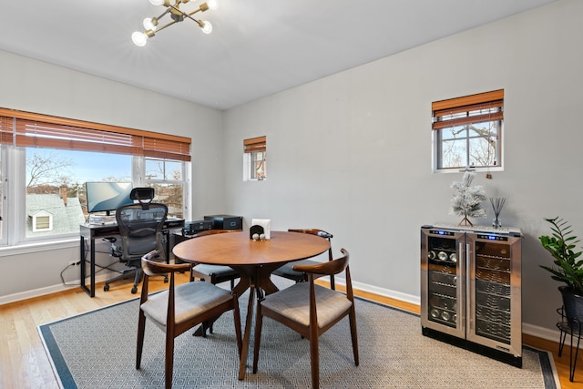 dining space featuring plenty of natural light, a chandelier, beverage cooler, and light hardwood / wood-style flooring