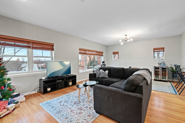 living room featuring a notable chandelier, beverage cooler, and light hardwood / wood-style flooring