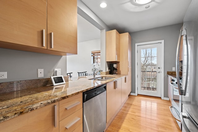 kitchen featuring appliances with stainless steel finishes, light brown cabinetry, light stone counters, sink, and light hardwood / wood-style floors