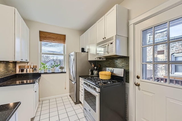 kitchen with light tile patterned flooring, white cabinetry, decorative backsplash, dark stone counters, and gas range