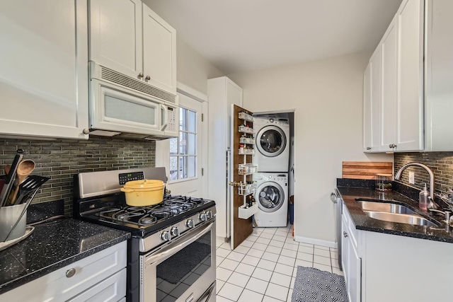 kitchen featuring stacked washer and dryer, gas range, sink, and white cabinets