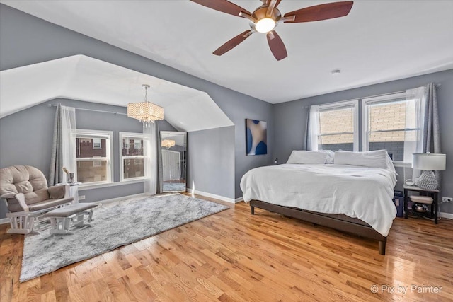 bedroom featuring hardwood / wood-style flooring, ceiling fan with notable chandelier, and lofted ceiling