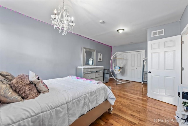 bedroom featuring a notable chandelier, light hardwood / wood-style floors, and a closet