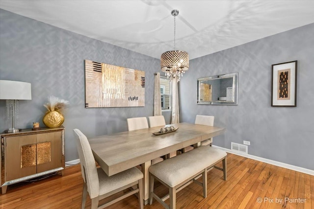 dining area with hardwood / wood-style flooring and a notable chandelier