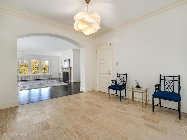 living area with arched walkways, radiator, crown molding, and baseboards