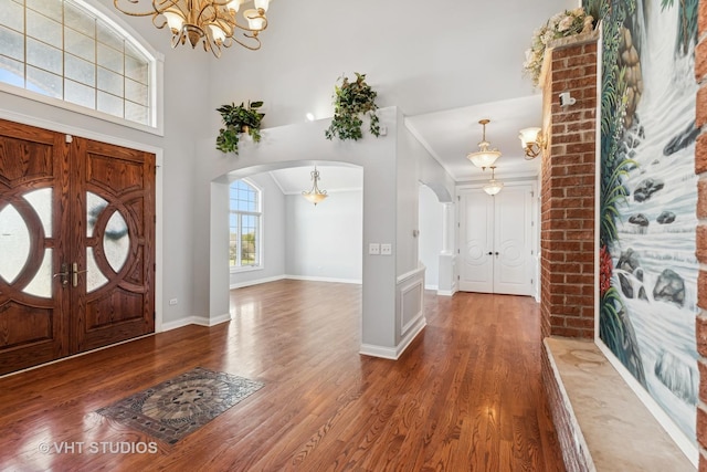 entryway featuring ornamental molding, dark wood-type flooring, and an inviting chandelier