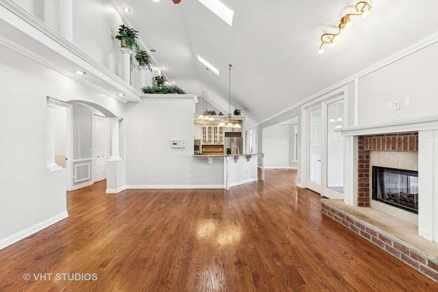 unfurnished living room featuring a fireplace, hardwood / wood-style floors, high vaulted ceiling, and crown molding