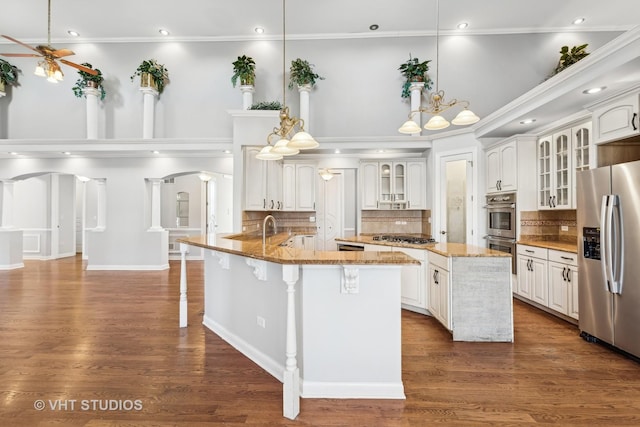 kitchen with a center island with sink, stainless steel appliances, decorative light fixtures, and hardwood / wood-style flooring