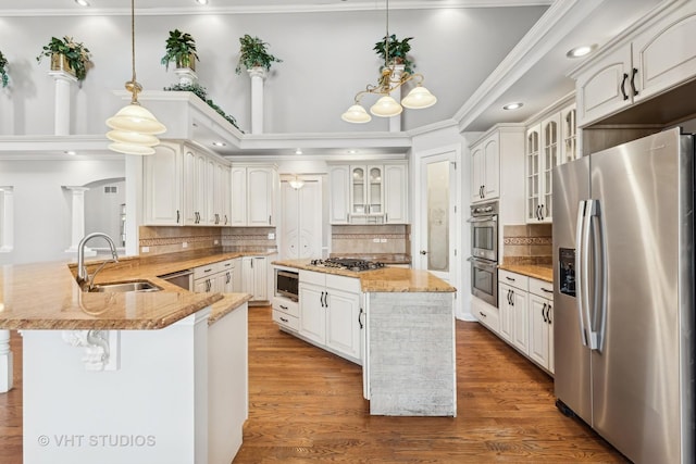 kitchen featuring pendant lighting, hardwood / wood-style floors, white cabinets, sink, and stainless steel appliances