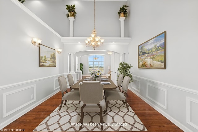 dining room with ornate columns, crown molding, dark hardwood / wood-style flooring, and a notable chandelier