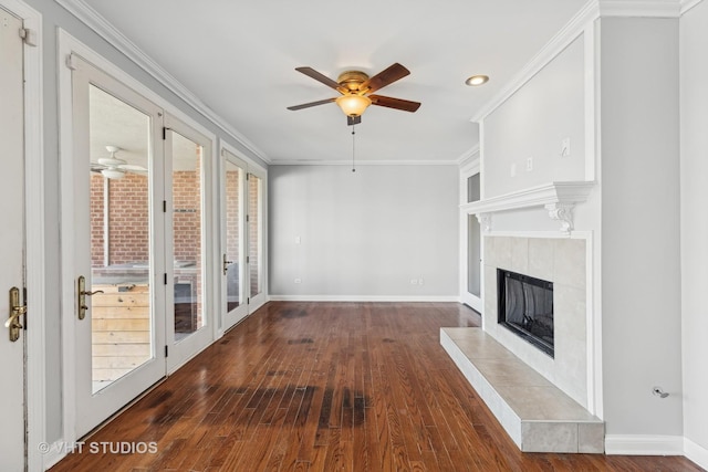 unfurnished living room with ceiling fan, dark hardwood / wood-style flooring, ornamental molding, and a tiled fireplace