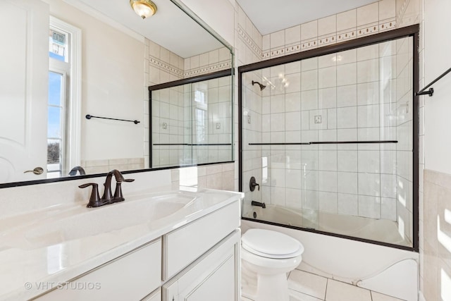 full bathroom featuring shower / bath combination with glass door, vanity, tile patterned floors, and toilet