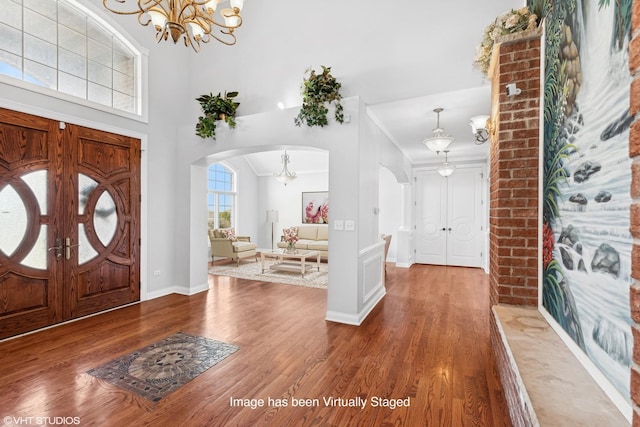 entryway featuring crown molding, wood-type flooring, and an inviting chandelier