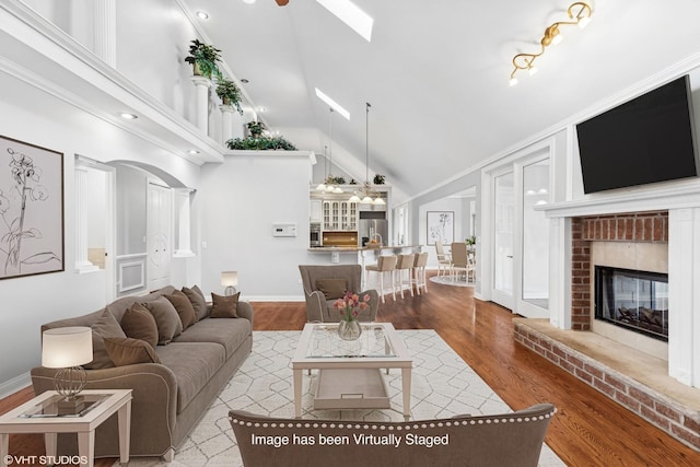 living room featuring a brick fireplace, high vaulted ceiling, and light hardwood / wood-style flooring