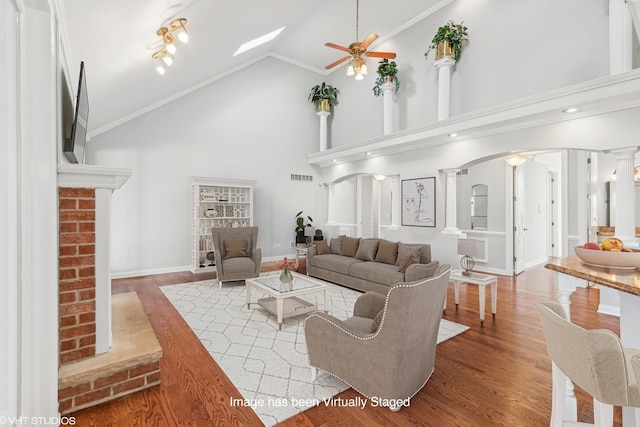 living room with high vaulted ceiling, hardwood / wood-style flooring, ornate columns, and crown molding