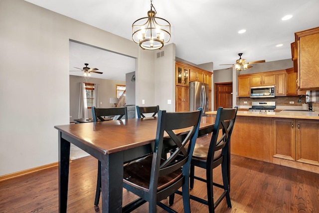 dining space with ceiling fan with notable chandelier, dark hardwood / wood-style flooring, and sink