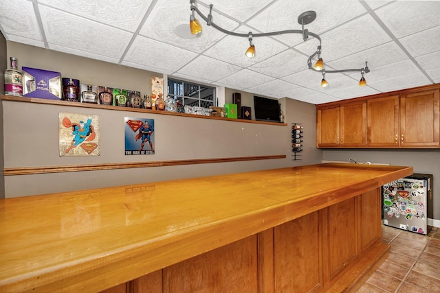 bar featuring a drop ceiling and light tile patterned flooring