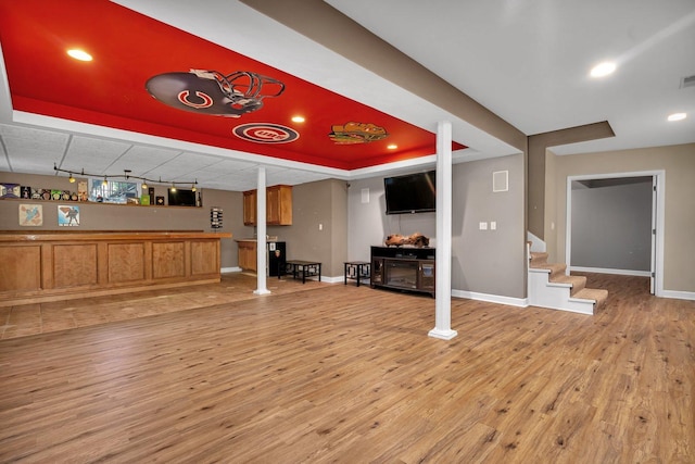 interior space with light wood-type flooring and a tray ceiling