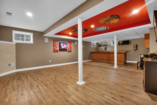 basement with bar and light hardwood / wood-style flooring