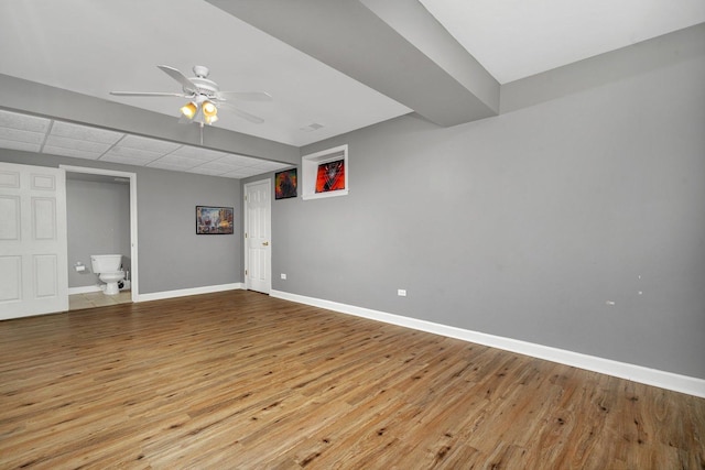 basement with a paneled ceiling, ceiling fan, and light wood-type flooring