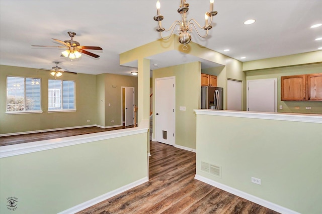 kitchen with hardwood / wood-style flooring, ceiling fan with notable chandelier, stainless steel fridge, and decorative light fixtures