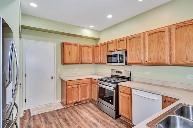 kitchen featuring appliances with stainless steel finishes, light hardwood / wood-style floors, and sink