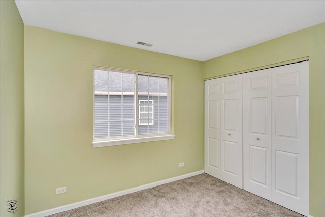 unfurnished bedroom with light carpet and a closet