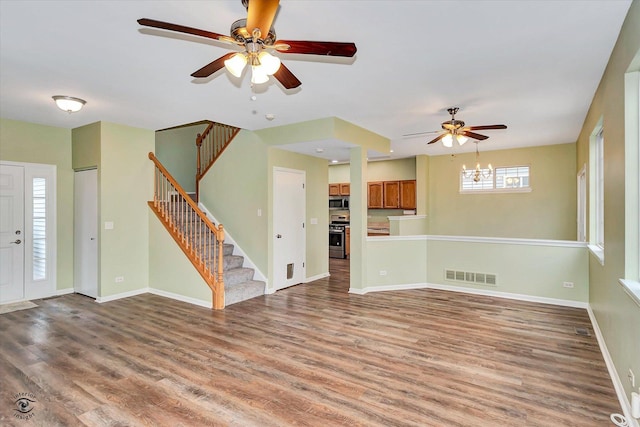 unfurnished living room featuring wood-type flooring and ceiling fan with notable chandelier