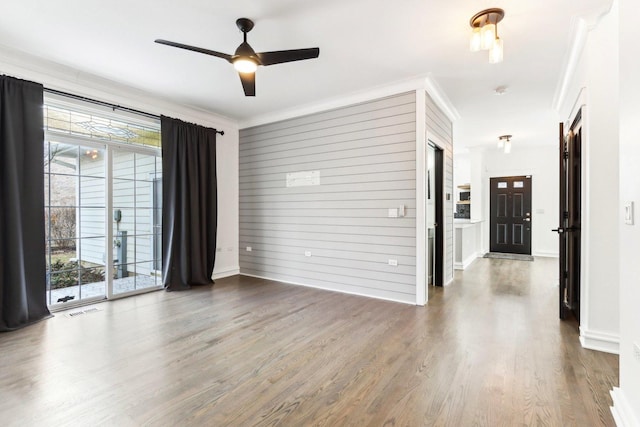 spare room with ceiling fan, hardwood / wood-style floors, wood walls, and ornamental molding