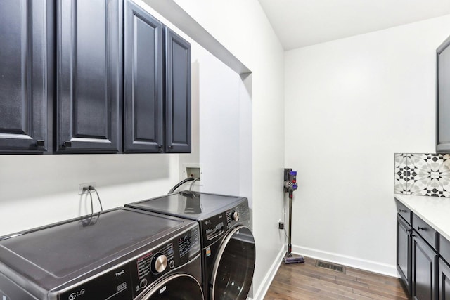 laundry room featuring cabinets, dark hardwood / wood-style flooring, and separate washer and dryer