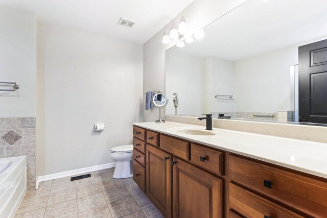 bathroom featuring tile patterned flooring, vanity, a bath, and toilet