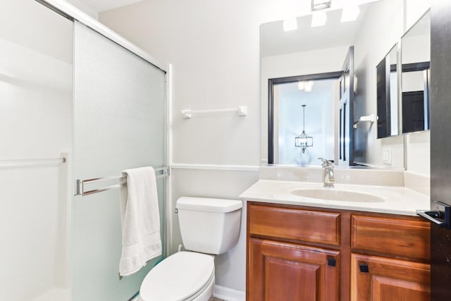 bathroom featuring vanity, toilet, and a shower with door