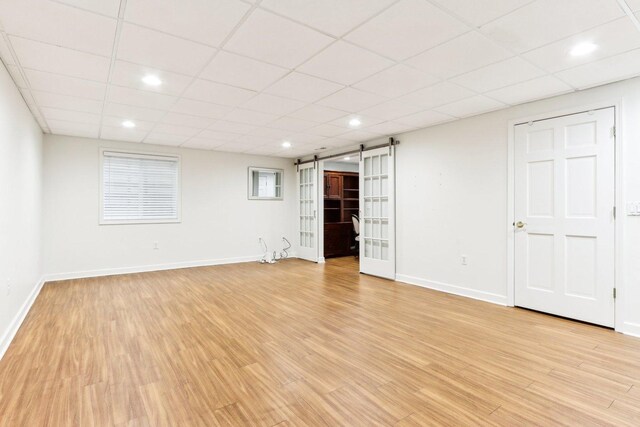 interior space with a barn door, light hardwood / wood-style floors, and a paneled ceiling