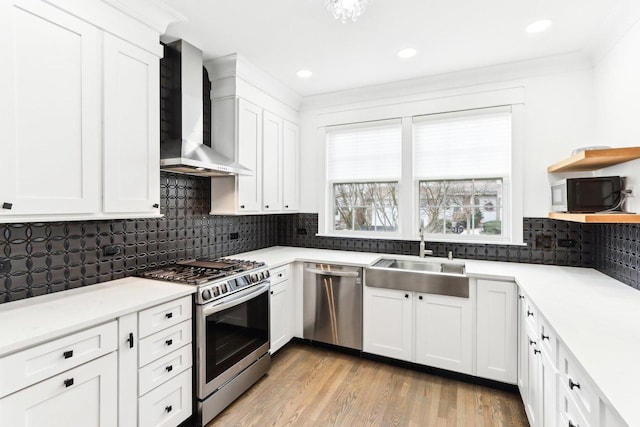 kitchen featuring sink, white cabinets, wall chimney range hood, and appliances with stainless steel finishes