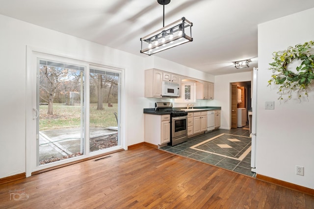 kitchen featuring dark hardwood / wood-style flooring, decorative light fixtures, white appliances, and sink