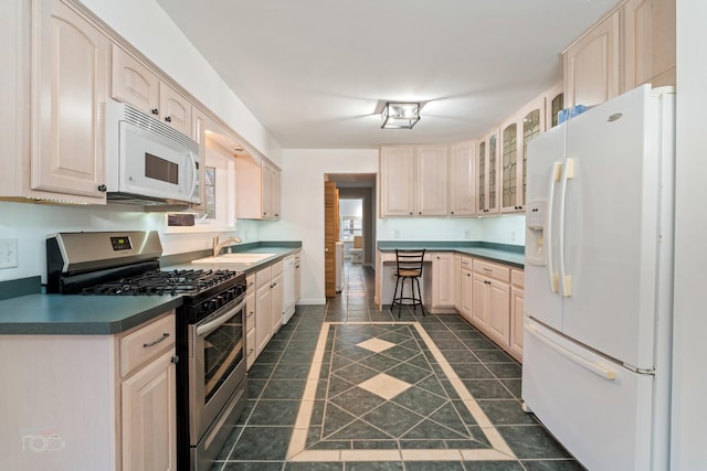 kitchen featuring light brown cabinetry, dark tile patterned floors, white appliances, and sink