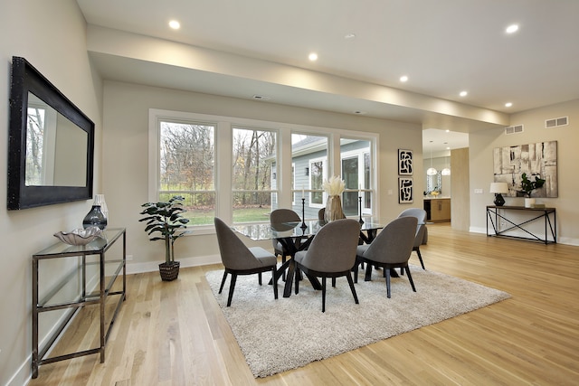 dining area with light hardwood / wood-style floors and a notable chandelier