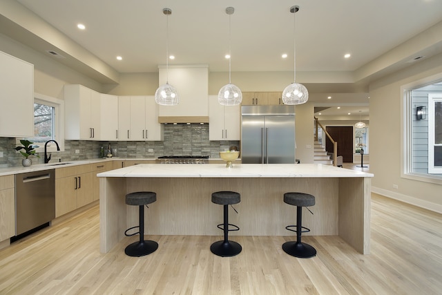 kitchen with premium range hood, a center island, light wood-type flooring, and appliances with stainless steel finishes