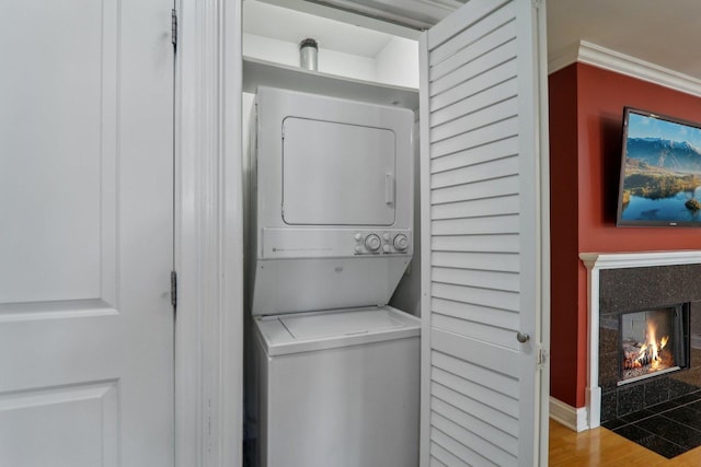 laundry area featuring light hardwood / wood-style flooring, stacked washer / drying machine, and a fireplace