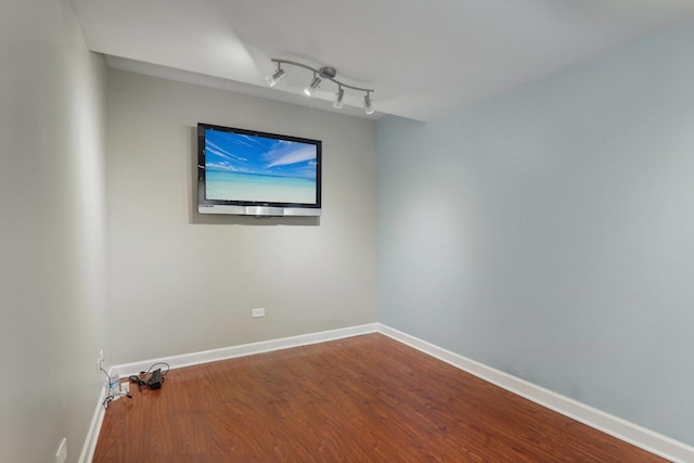 unfurnished room with track lighting and wood-type flooring