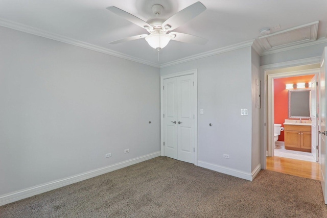 unfurnished bedroom featuring carpet floors, sink, ceiling fan, crown molding, and a closet