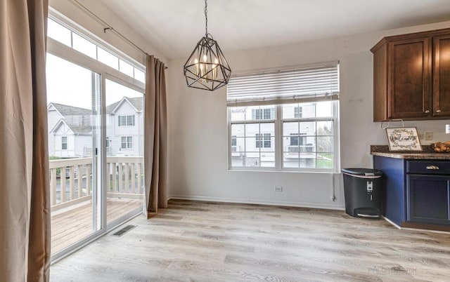 unfurnished dining area featuring light hardwood / wood-style floors and a notable chandelier