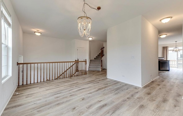 unfurnished room with light hardwood / wood-style flooring and an inviting chandelier