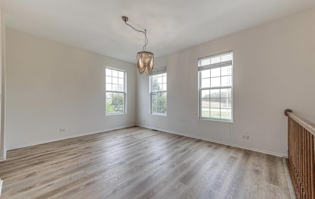 unfurnished room featuring a chandelier and light hardwood / wood-style floors