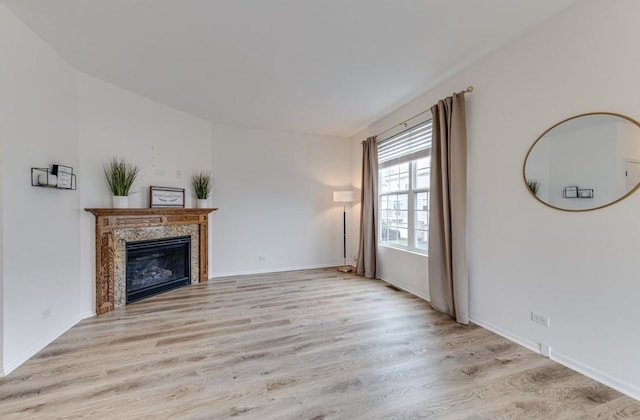 unfurnished living room with a high end fireplace and light hardwood / wood-style flooring